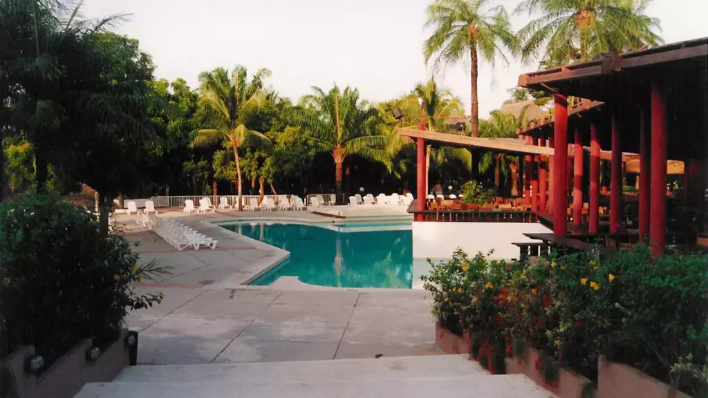 Piscine entourée de palmiers dans un village de vacances